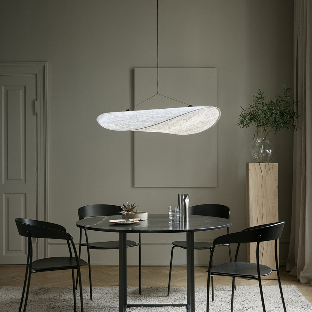 A dining room with a New Works Tense Pendant Lamp hanging above a table and chairs.