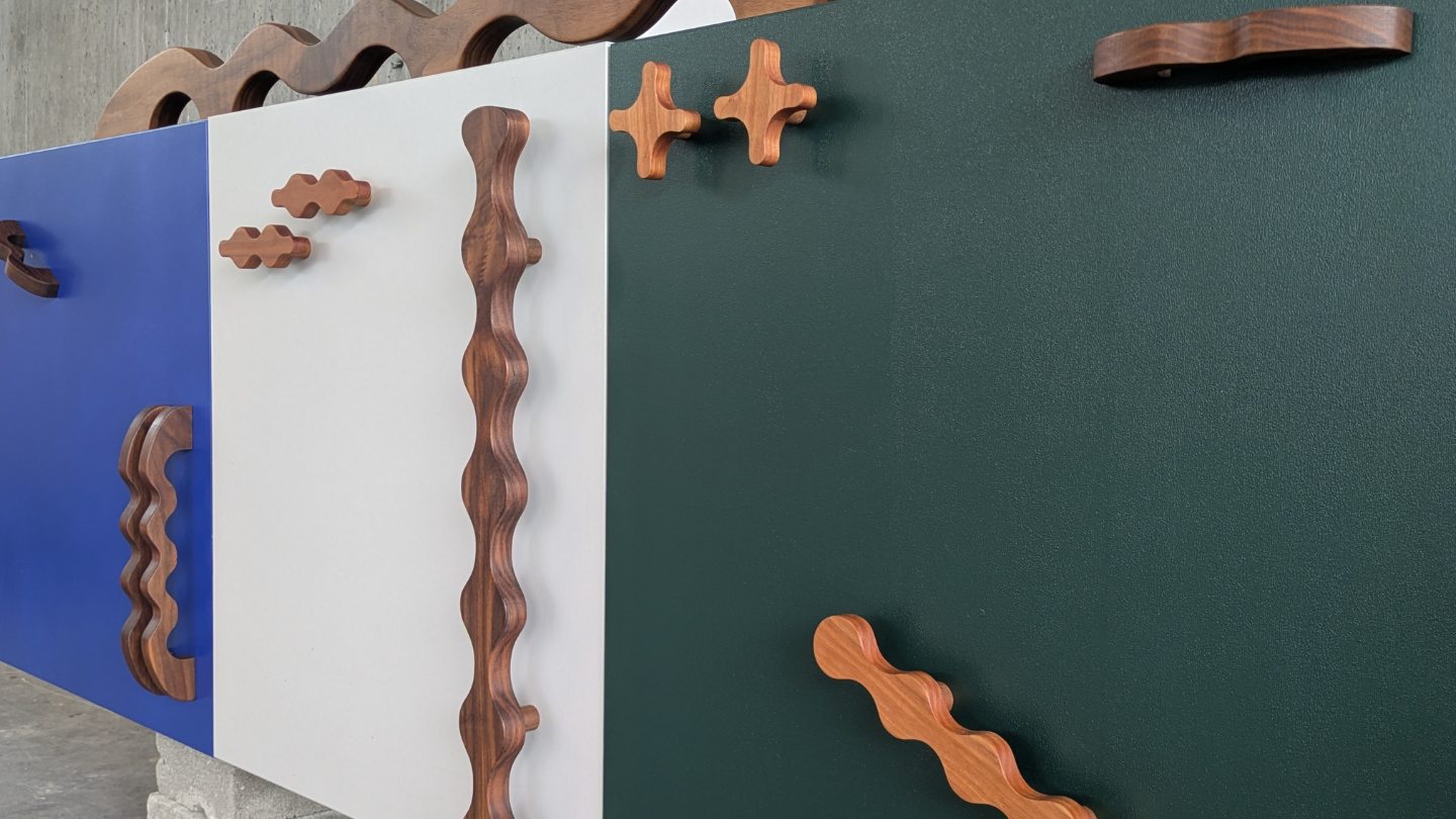 Various squiggly and wavy wood cabinet handles on a colorful dresser cabinet. 