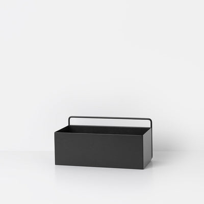 A black Ferm Living Wall Box sitting on top of a white table.