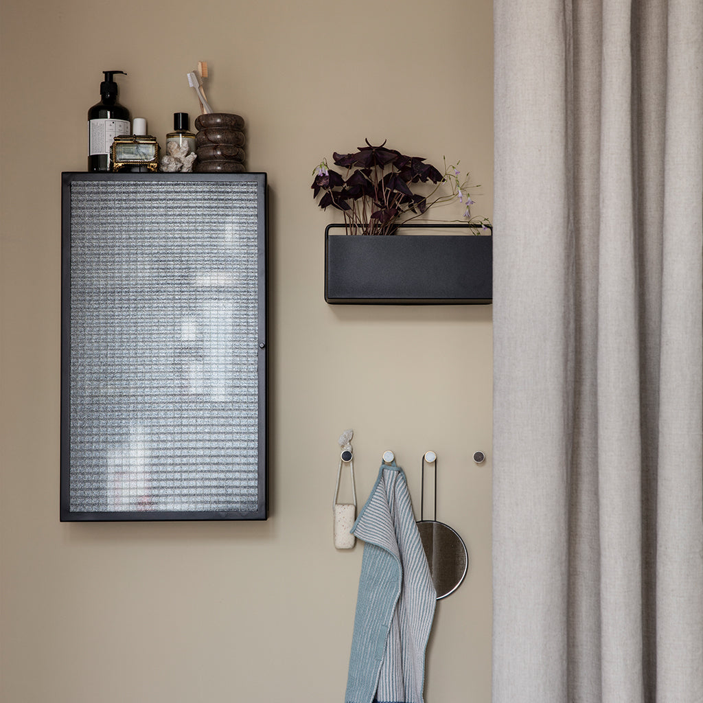 A Ferm Living Wall Box air conditioner next to a window.