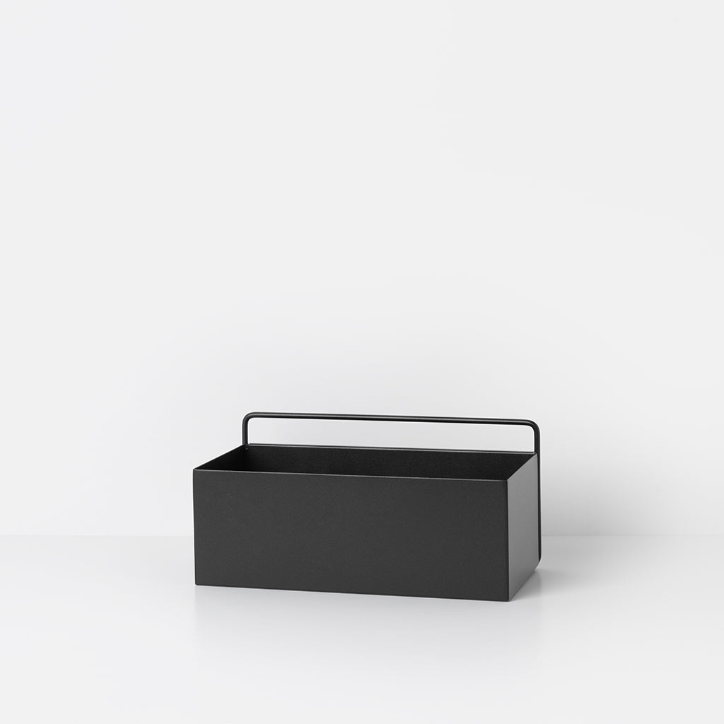 A black Ferm Living Wall Box sitting on top of a white table.