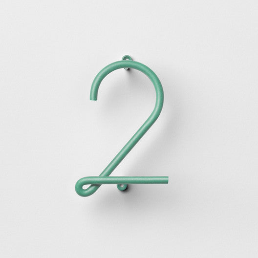 A pair of NakNak Wire Number Colours hooks in green on a white wall.