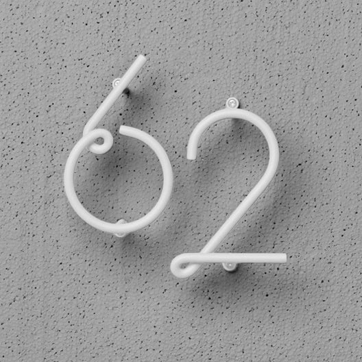 A pair of NakNak Wire Number Neutral ear hooks on a wall.