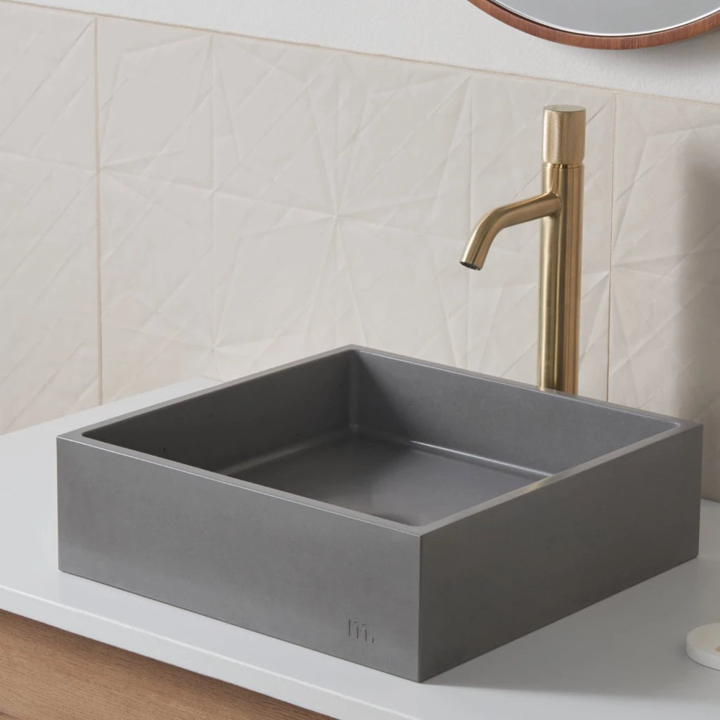 A mudd. concrete Yarra Basin SM bathroom sink with a gold faucet and a mirror above it.