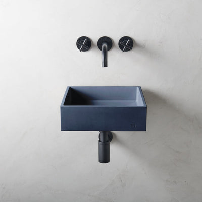 A mudd. concrete Yarra Basin SM Affix sink with two black faucets on the wall.