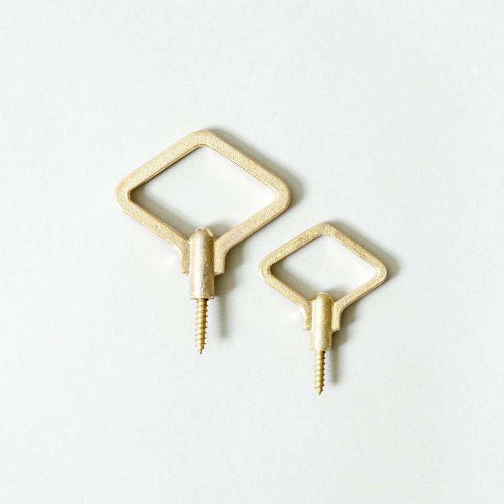 A pair of Oji Masanori Zenmai Brass Hooks on a white surface.