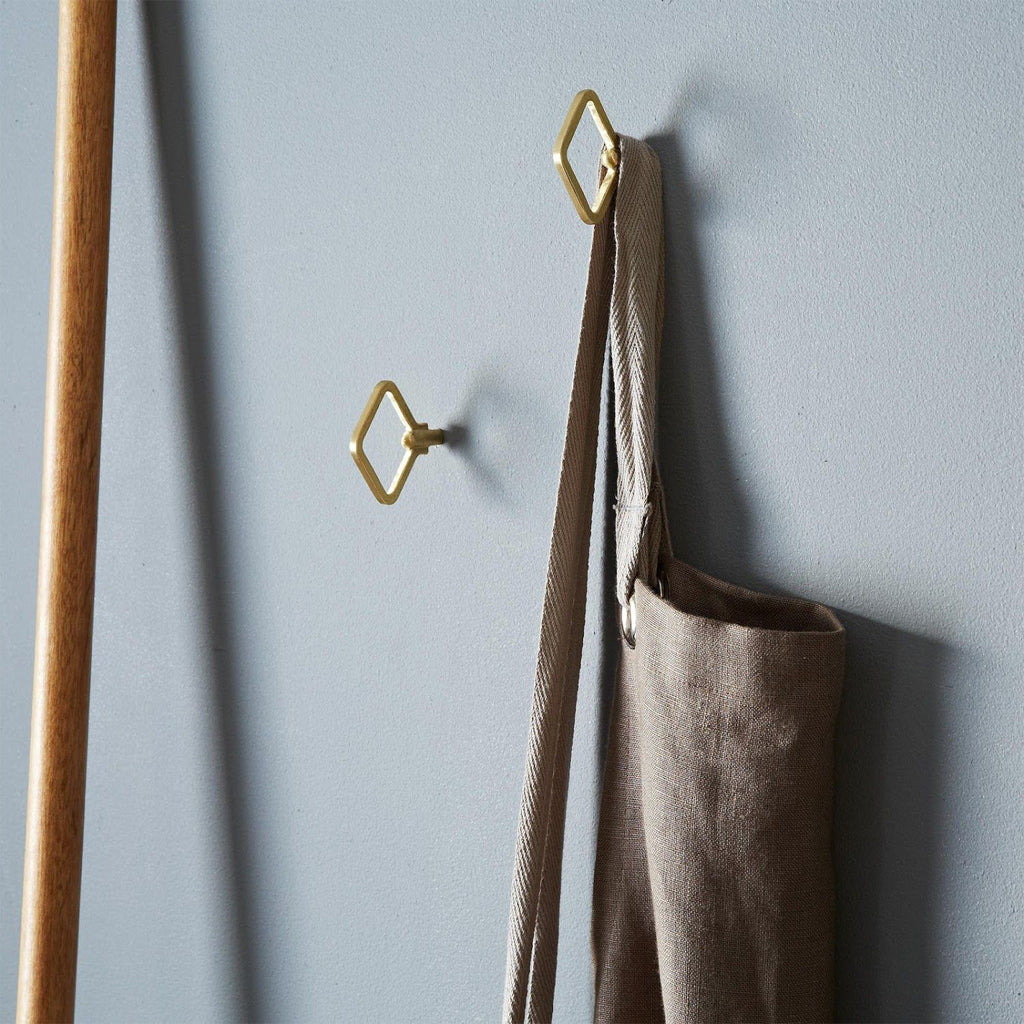 A pair of Oji Masanori Zenmai Brass Hooks on a wall next to a bag.