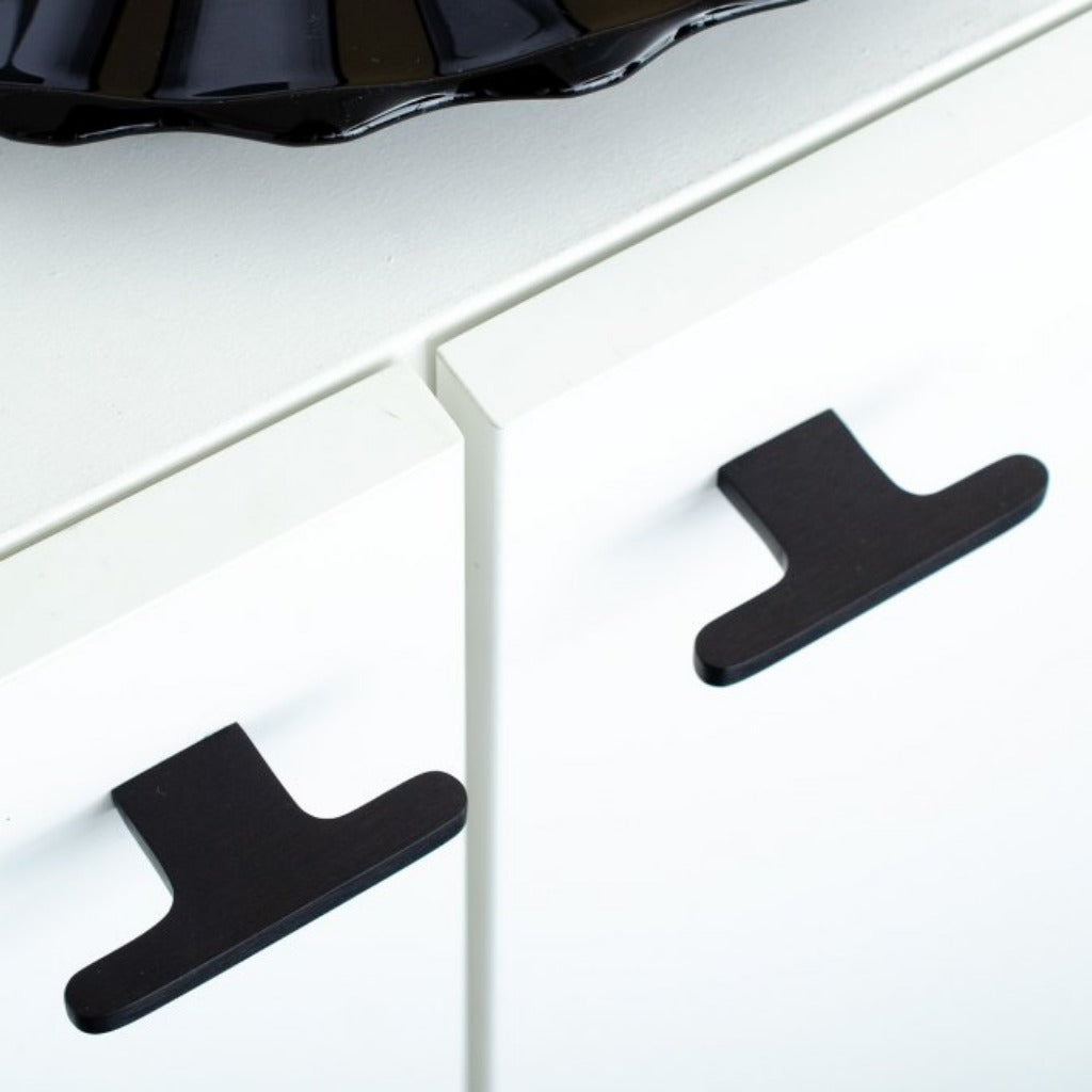T shaped knobs in black mounted on a white cabinet