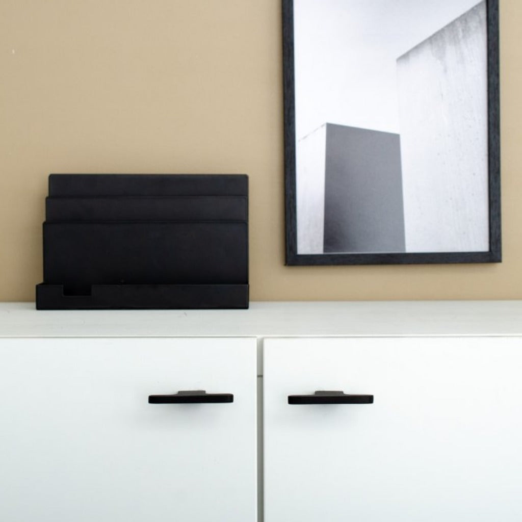 T shaped knobs in black mounted on a white cabinet