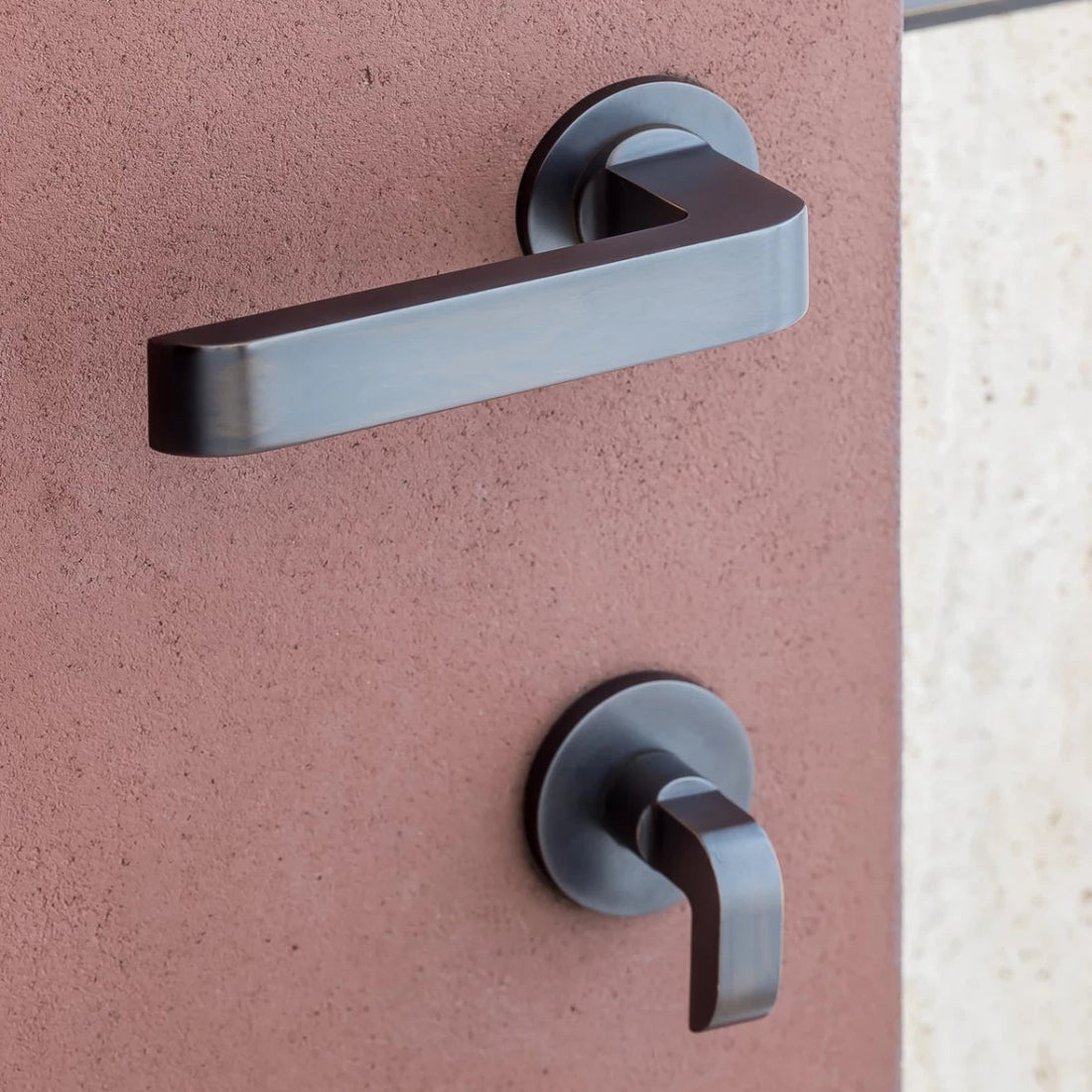 Brass Vervloet Audrey door knob on a pink door beside botanical wallpaper