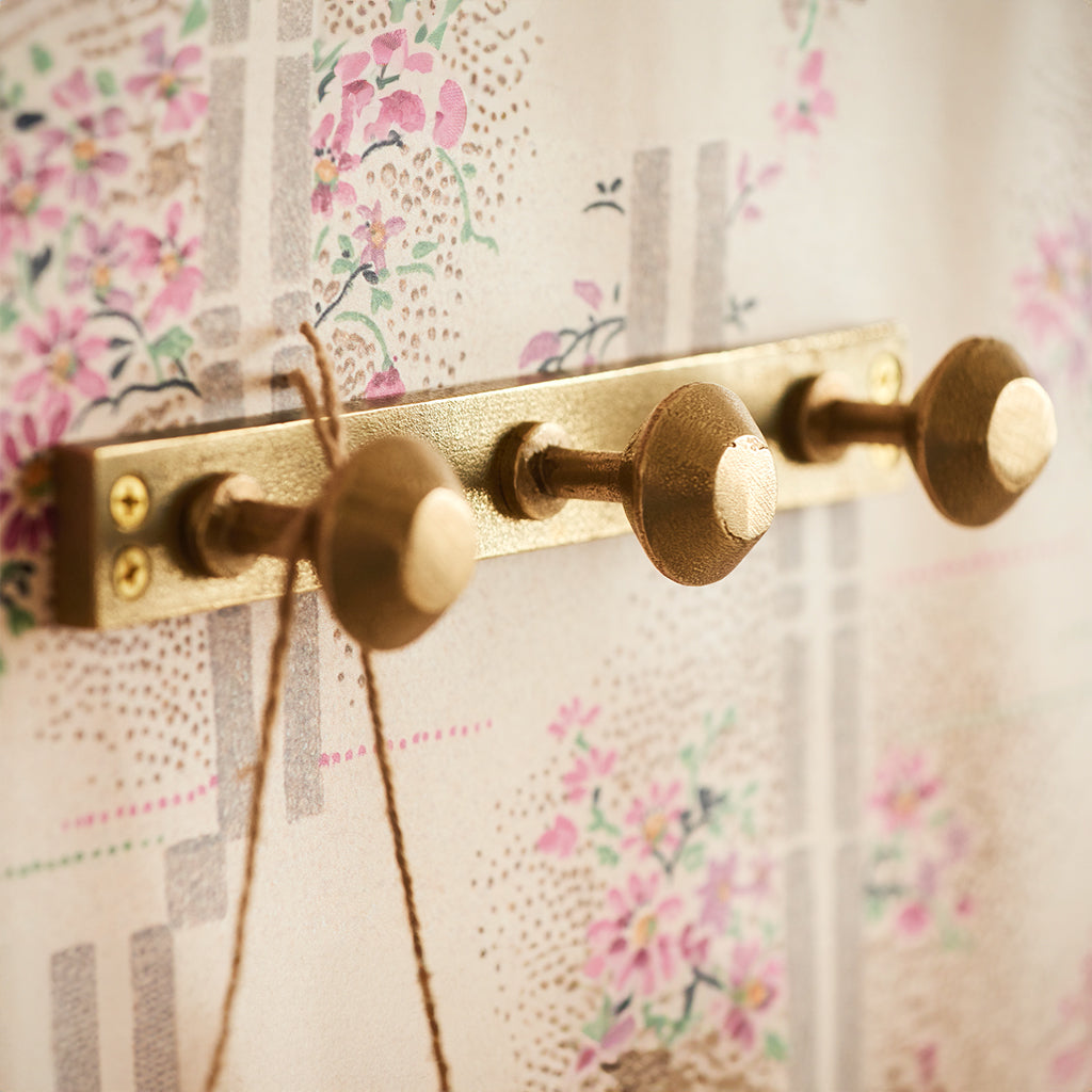 Spul Knob on backplate in satin brass installed on wallpapered wall